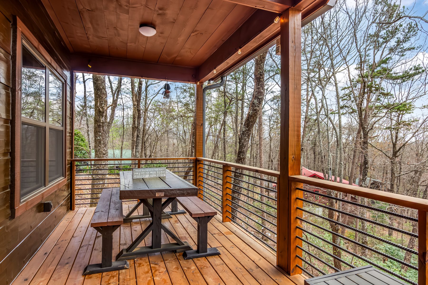 Covered porch with cable railings overlooking the woods