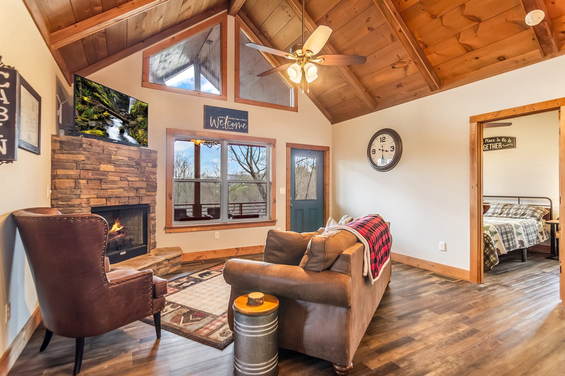 Living area with stone fireplace, leather seating, and view into a bedroom