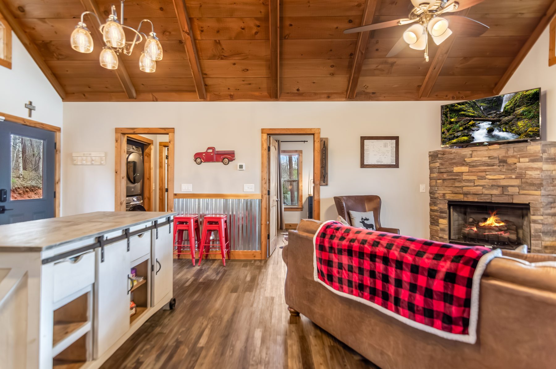 Living and dining open layout with stone fireplace, leather sofa, and kitchen island