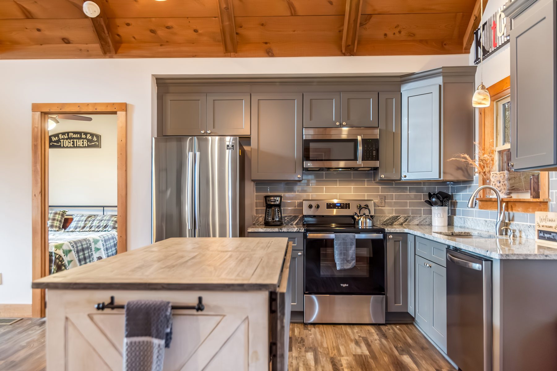 Kitchen with stainless appliances, butcher-block island, view through to a bedroom