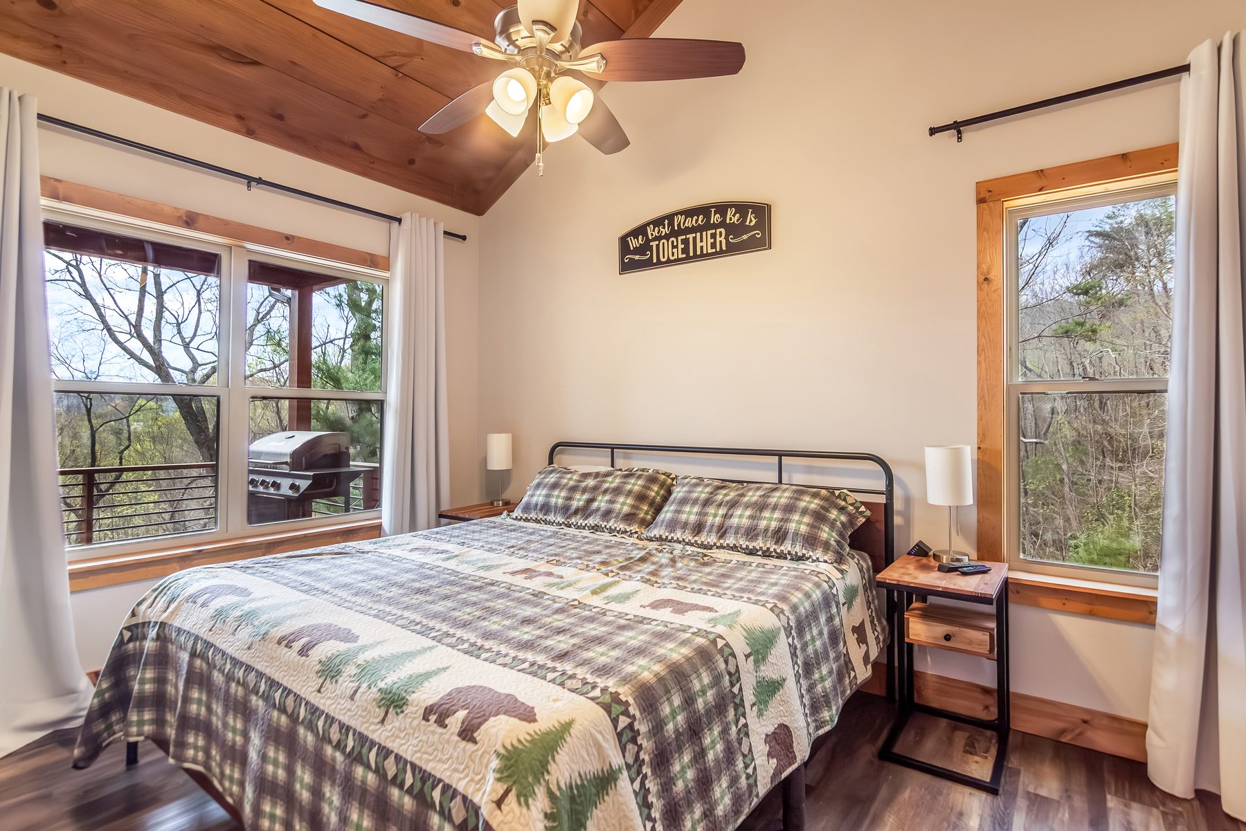 Queen bedroom with bear quilt, Best Place to Be is Together sign, view of the deck grill