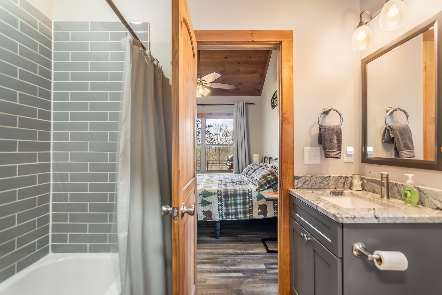 Bathroom with tub, granite vanity, view through to a bedroom and the deck beyond
