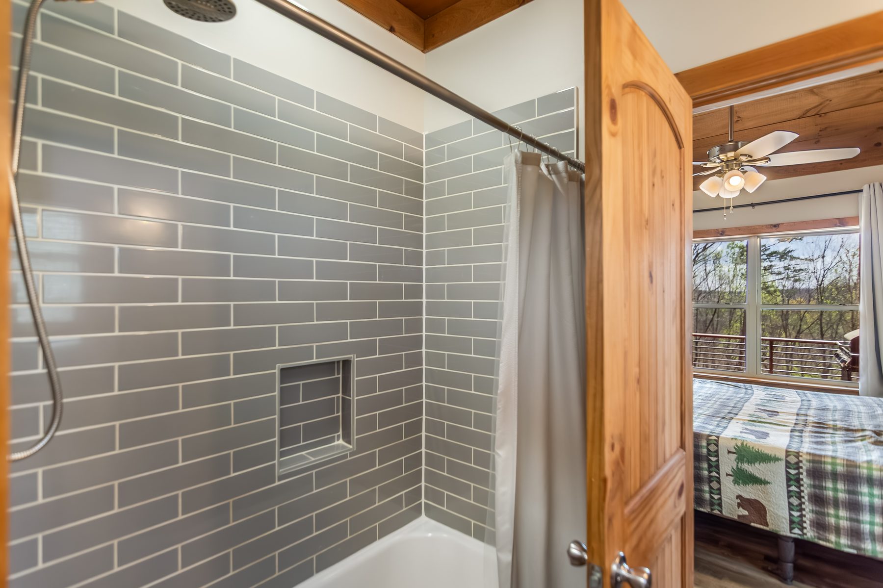 Walk-in tile shower with niche, view through the doorway to a bedroom