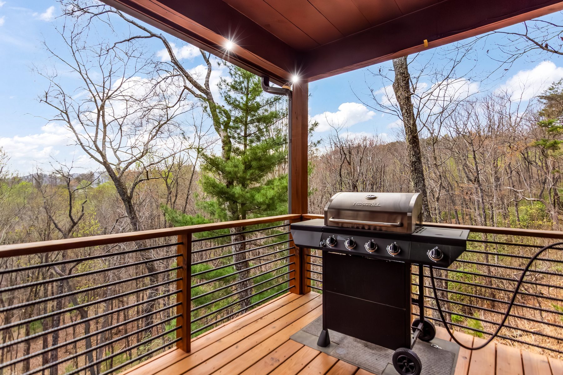 Gas grill on the covered deck with mountain views through the trees